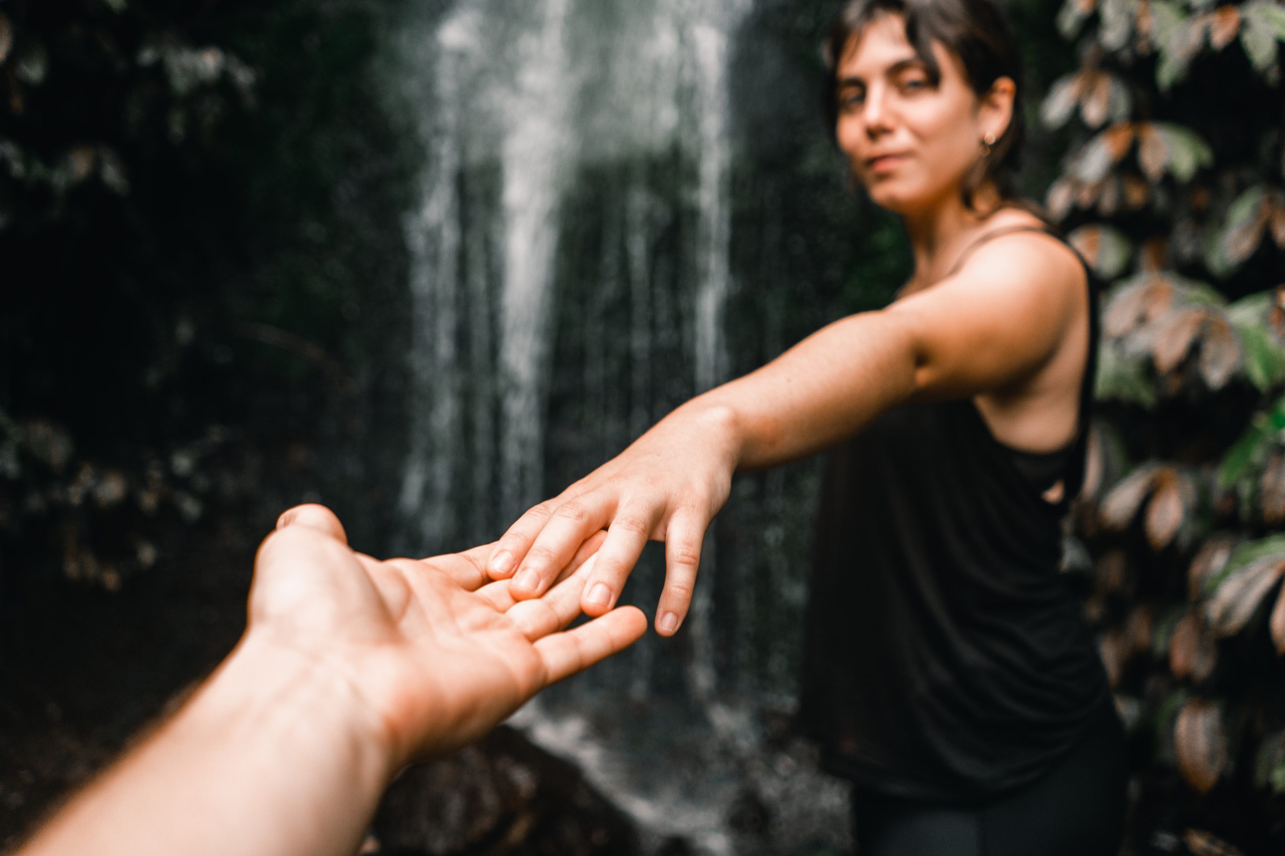 Pareja conectando y cogidos de la mano frente a una cascada en un entorno natural, simbolizando acompañamiento emocional en Caminar Creciendo, Sevilla.