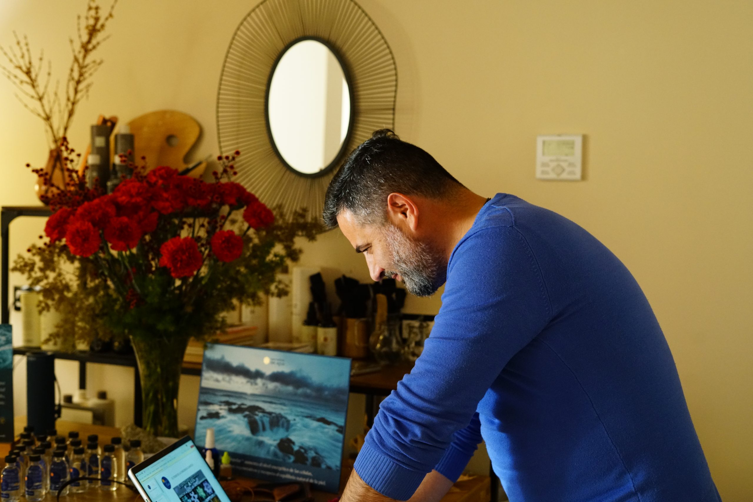 Hombre trabajando concentrado en su portátil dentro de un espacio acogedor decorado con flores, esencias y elementos naturales; imagen capturada en Caminar Creciendo, Sevilla, reflejando dedicación y armonía en el entorno de trabajo terapéutico.