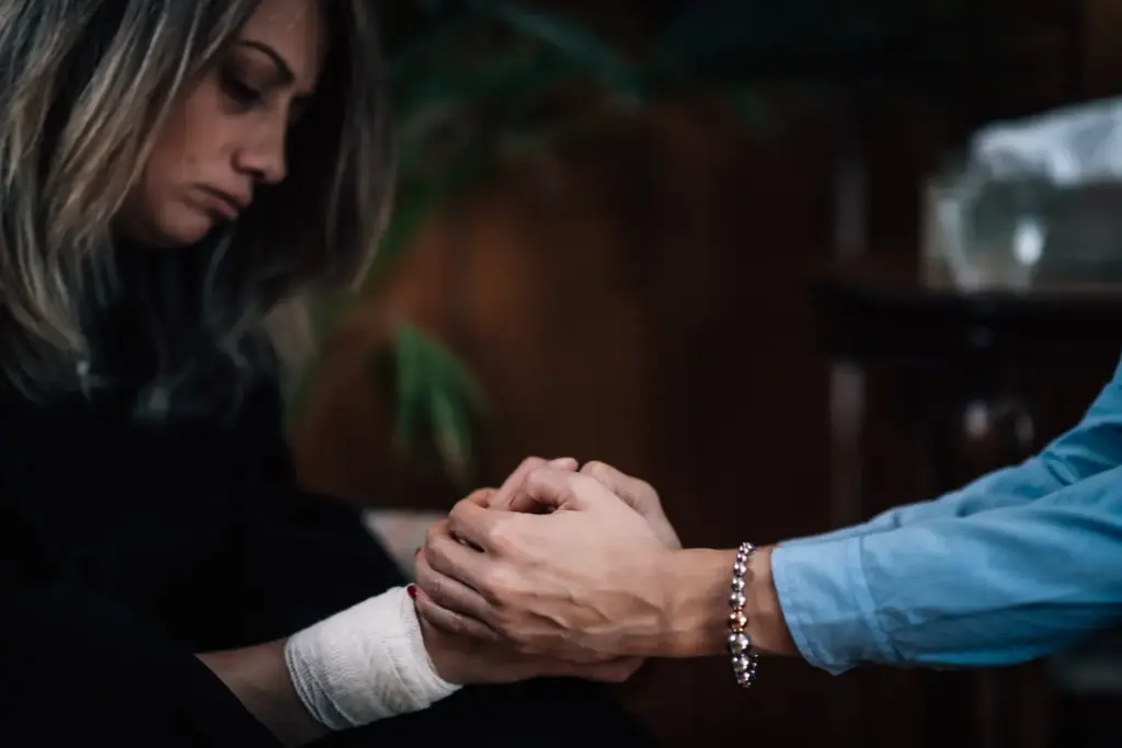 Terapeuta sosteniendo con ambas manos las de una mujer durante una sesión de acompañamiento en el duelo